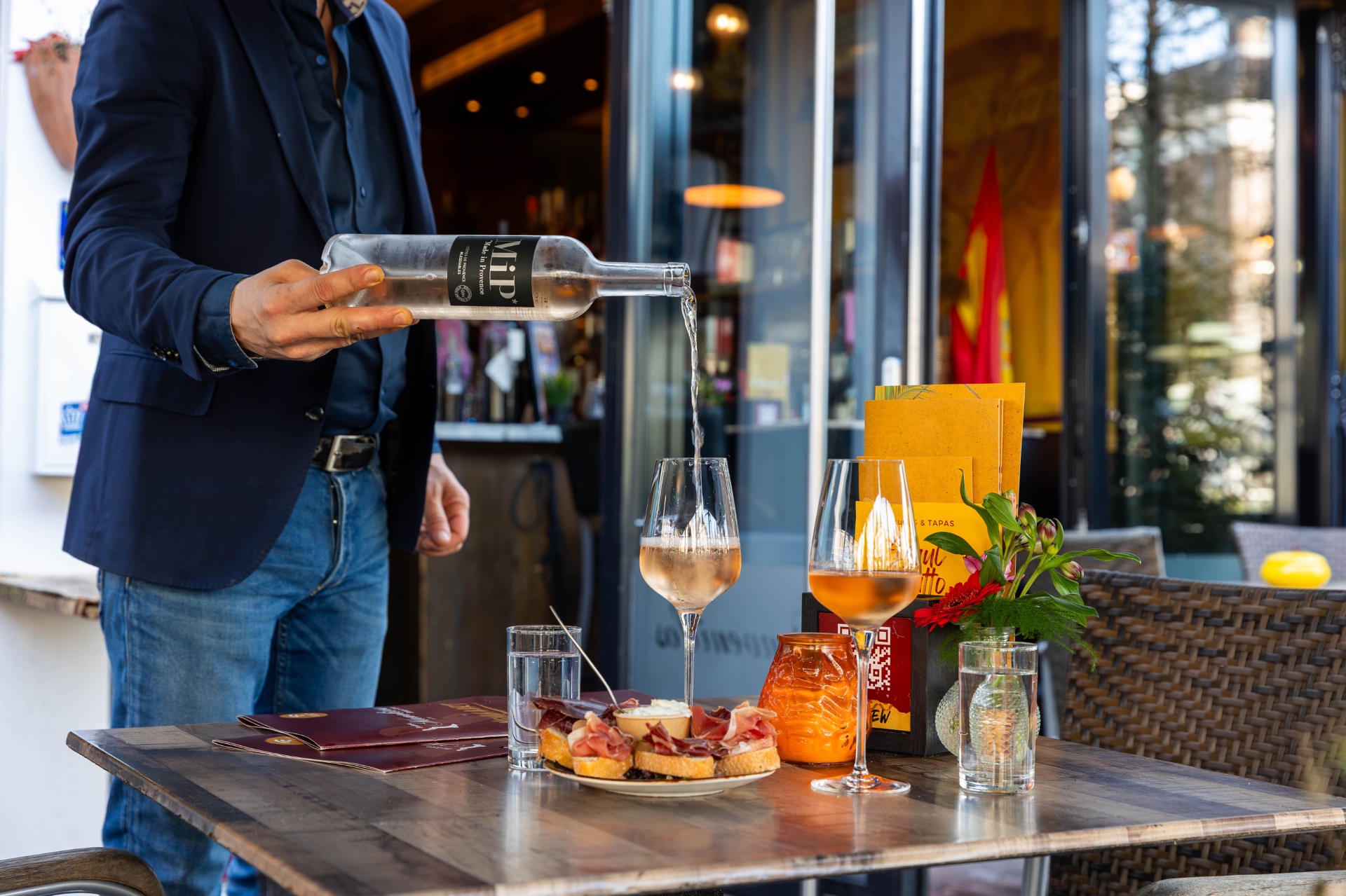 Wijn wordt ingeschonken aan een tafel met tapas