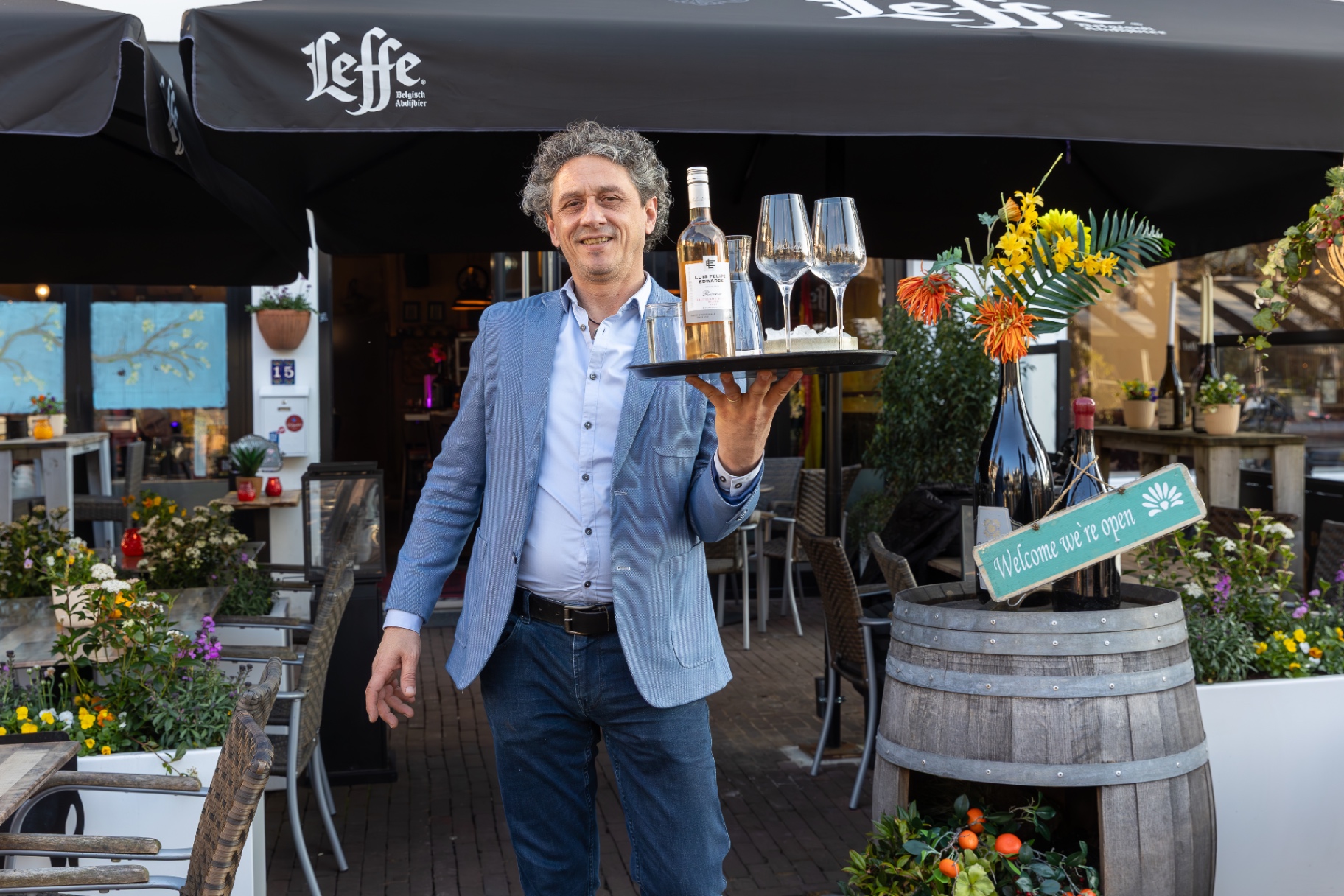Mano op het terras met een dienblad vol wijnglazen
