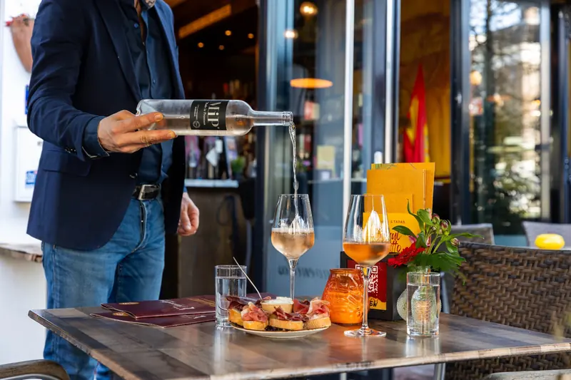 Wijn wordt ingeschonken aan een tafel met tapas