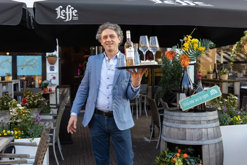 Mano op het terras met een dienblad vol wijnglazen